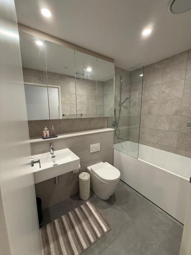 a bathroom with a toilet and a sink and a tub at The Gosford Modern Nest in Gosford