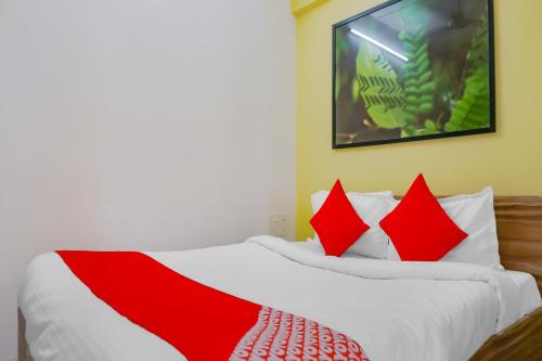 浦那Collection O Baner Hillview Pune Formerly Siri Lodge的卧室里有一张床，上面有红色和白色的枕头