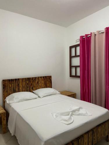 a bedroom with a large white bed with red curtains at MONTROND House in São Filipe