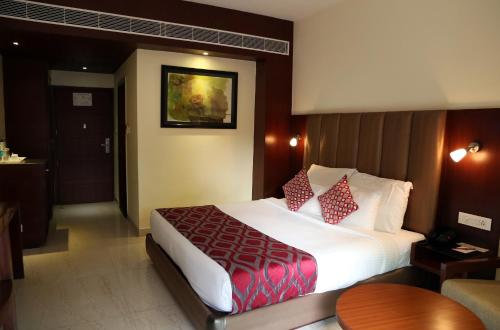 a hotel room with a large bed with red pillows at Hotel Cama in Chandīgarh