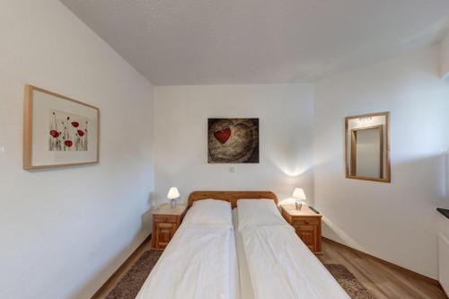 a white bedroom with a bed and two night tables at Großzügige Ferienwohnung für bis zu 9 Personen in Burhave