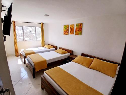 a room with three beds and a window at HOTEL LA RUEDA SR in Barbosa