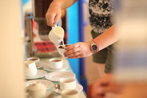 a woman pouring coffee into a cup on a table at Palago mc Hotel Park View in Ho Chi Minh City