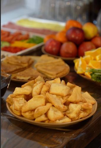 Un plato de patatas fritas y fruta sobre una mesa en Hills Hotel, en Karakol