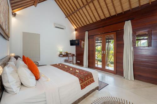 a bedroom with a large white bed with wooden walls at Villa Tegal Tis Ubud in Payangan