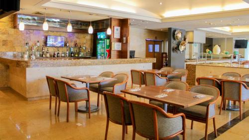 Un restaurante con mesas y sillas de madera y un bar. en Holiday Inn Orizaba by IHG, en Orizaba