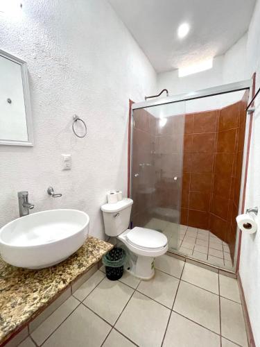 a bathroom with a sink and a toilet and a shower at Hotel y Bungalows Bugambilias in San Patricio Melaque