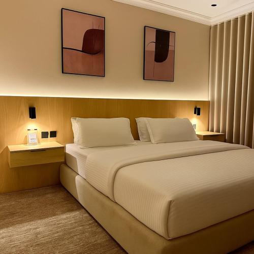 a bedroom with a large white bed with two lamps at نسيم الحرم 3 in Ash Shishah