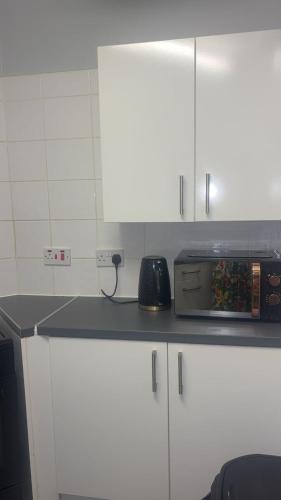 a kitchen with white cabinets and a counter top with a microwave at Ayish in Birmingham