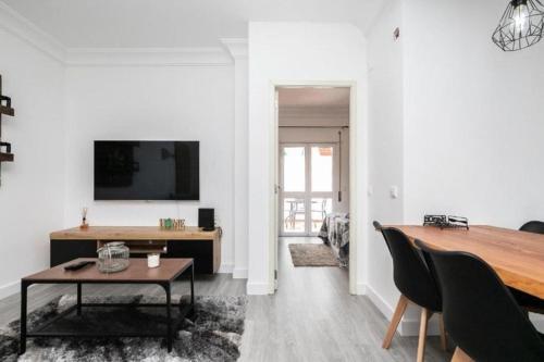 un soggiorno con un tavolo e una TV a parete di Cabanas Coastal Escape a Tavira