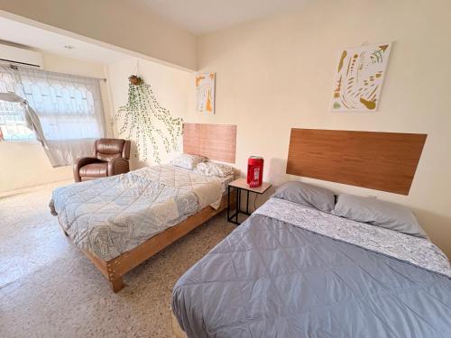 a bedroom with two beds and a chair at Casona el Sol in Veracruz