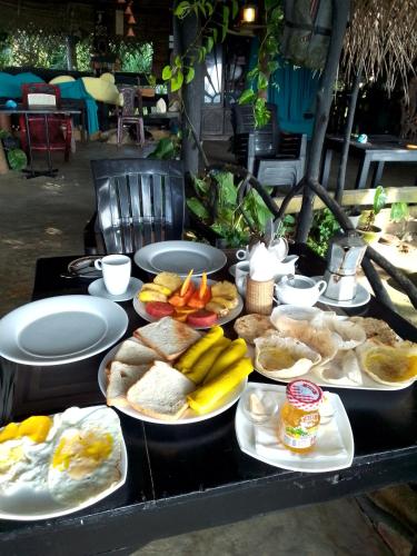 a table with plates of bread and fruit on it at Happybeach Sea view Cabin restaurant & beach bar in Tangalle