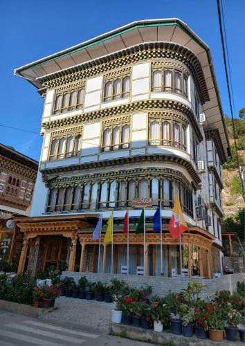 Hotel ZhuSa في Pajo: مبنى طويل مع أعلام أمامه