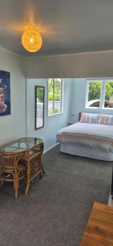 ein Schlafzimmer mit einem Bett und einem Glastisch in der Unterkunft Ebony Cottage in Mangawhai