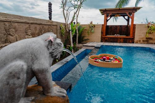Eine Statue eines Affen, der Wasser aus einem Pool trinkt in der Unterkunft Kamania Villa Ubud by Dhananjaya Hospitality in Tampaksiring