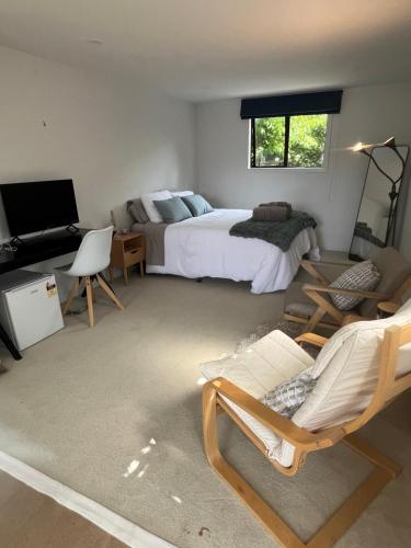 ein Schlafzimmer mit einem Bett und einer Couch und einem Fernseher in der Unterkunft Myrtle St Guesthouse in Auckland