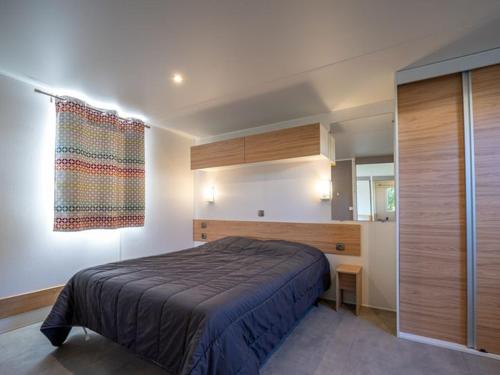a bedroom with a large bed and a window at Mobil-home Adapté PMR avec Terrasse à Notre-Dame-de-Monts - API-1-52-664 in Notre-Dame-de-Monts