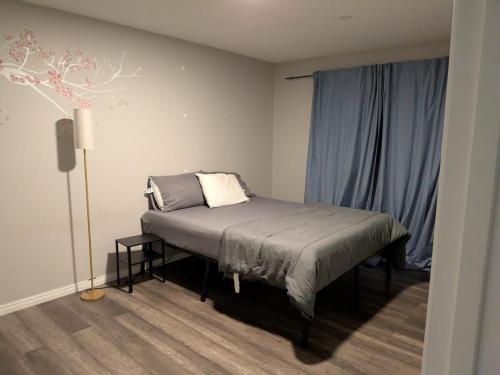 a bedroom with a bed and a lamp and blue curtains at Cozy Belleville Retreat Near DT & Waterfront in Belleville