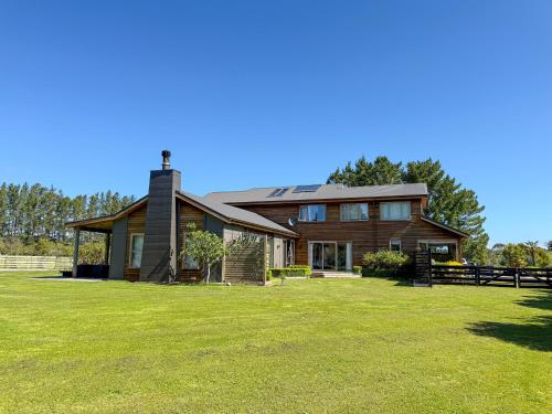 a large house with a grass field in front of it at Whispering Pines in Kaihinu