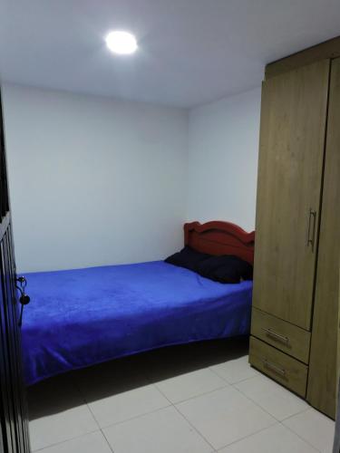 a bedroom with a blue bed and a cabinet at Confortable Apartamento Norte de Popayán in Popayan