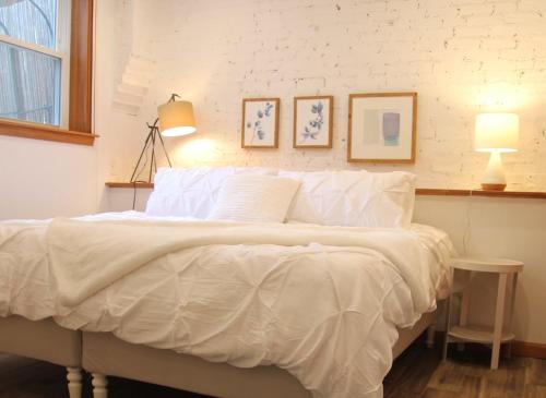a bedroom with a white bed with two pictures on the wall at Brighton guest suite in Boston