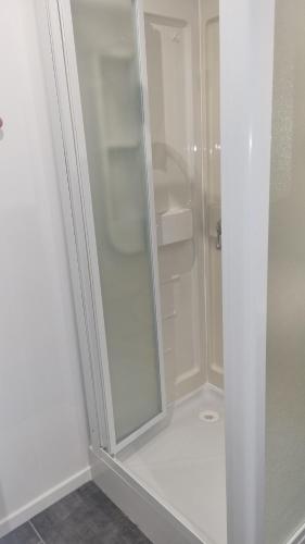 La salle de bains est pourvue d'une douche blanche avec une porte en verre. dans l'établissement Maisonnette avec jardin Reims centre, à Reims
