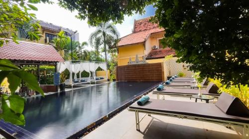 a swimming pool with tables and chairs next to a building at Villa Indochine d'Angkor in Siem Reap