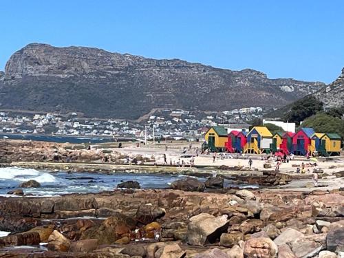 a group of colorful beach houses on a rocky beach at Pearlfields House Kalk Bay in Kalk Bay