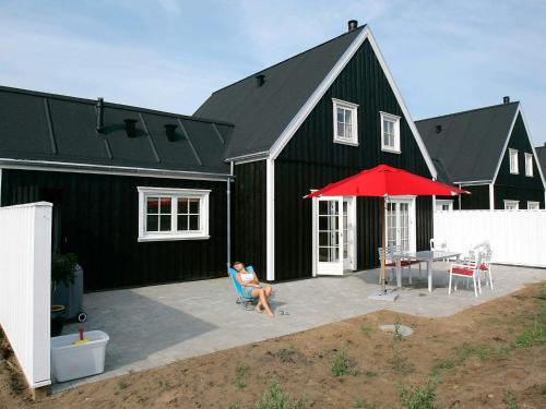 a woman sitting on a chair in front of a black house at 5 star holiday home in Blokhus in Blokhus