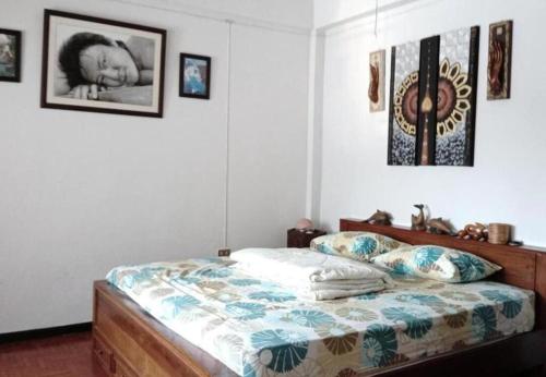 een slaapkamer met een bed en foto's aan de muur bij OhoWowGood in Chiang Mai