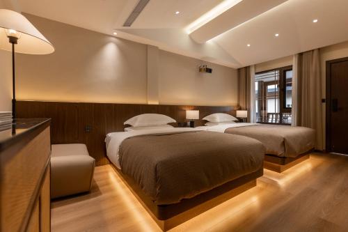 a bedroom with two beds and a desk and a television at 院中院喜与漫渡酒店丽江忠义市场店 in Lijiang