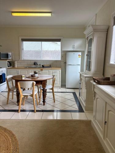 a kitchen with a table and chairs and a refrigerator at Stay - East Wynyard Beach in Wynyard