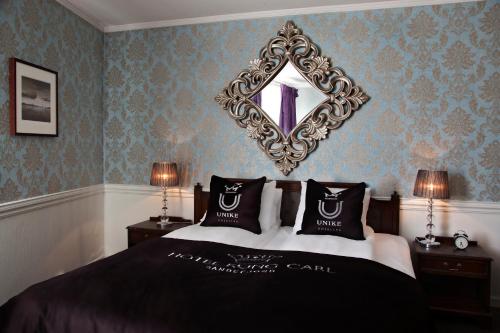 a bedroom with a bed with a mirror on the wall at Hotel Kong Carl - Unike Hoteller in Sandefjord