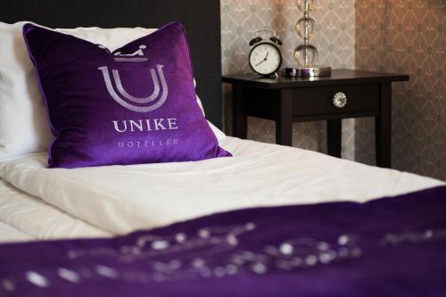 a purple pillow sitting on top of a bed at Hotel Kong Carl - Unike Hoteller in Sandefjord