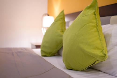 two lime green pillows sitting on a bed at Samed Big Tree in Ko Samed