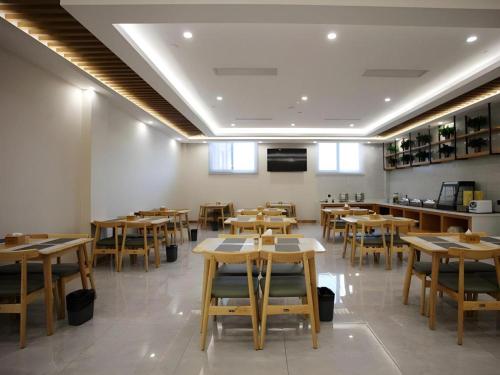 a dining room with wooden tables and chairs at GreenTree Inn Heze Shan County New Bus Station in Shan