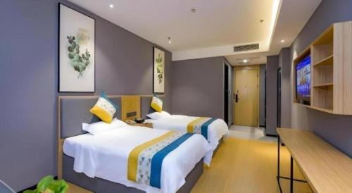 two beds in a hotel room with a television at GreenTree Inn Express Fuzhou Minhou County Mindu Custom Park in Minhou