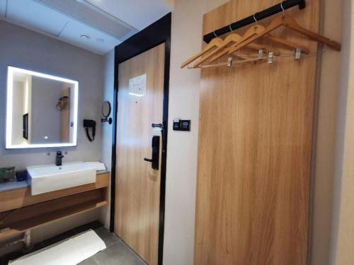ein Badezimmer mit einer Holztür und einem Waschbecken in der Unterkunft Green Tree Inn Express Shanghai Bund Yuyuan Xiaonanmen Metro Station in Shanghai