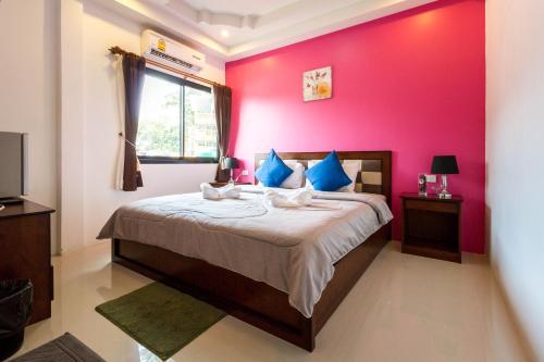a bedroom with a bed with a pink wall at Samed Big Tree in Ko Samed