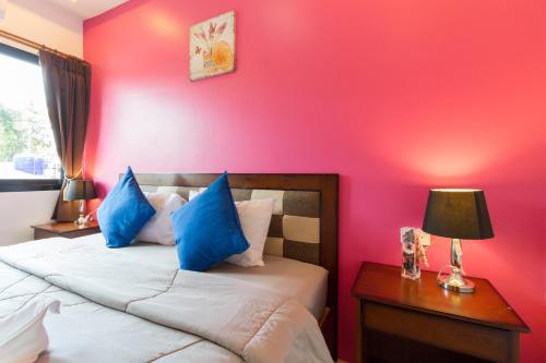 a bedroom with a red wall and a bed with blue pillows at Samed Big Tree in Ko Samed