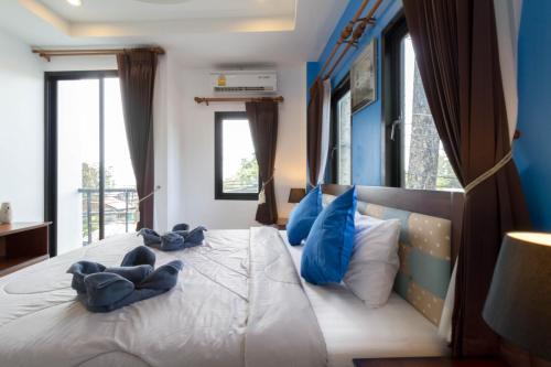 a bedroom with blue walls and a bed with blue pillows at Samed Big Tree in Ko Samed