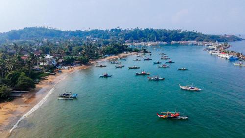 a group of boats in the water on a beach at Sithujaya Green Mirissa in Mirissa
