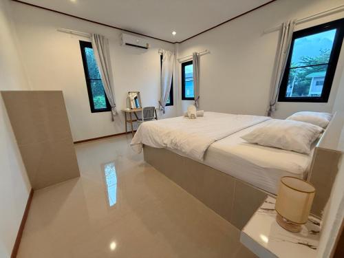 una camera con un grande letto e due finestre di Spacious House in Srithanu a Ko Kong Nui