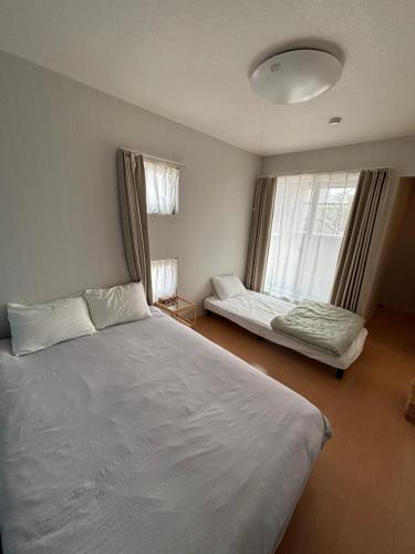 a bedroom with a large white bed and a window at 一棟貸切の民宿 月 駐車場2台無料 バス停徒歩1分 市街地へ好アクセス in Matsuyama