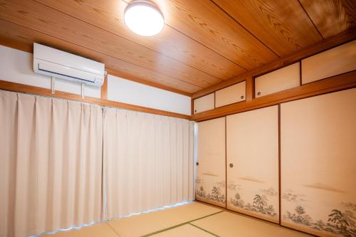 Cette chambre est dotée de murs en bois et d'un plafond avec un ventilateur. dans l'établissement 宿 重富 Stay SHIGETOMI, à Aira