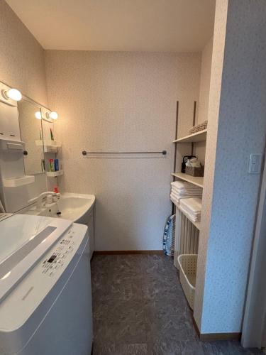 a white bathroom with a sink and a tub at 民泊 月 in Matsuyama