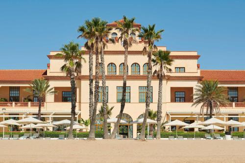 a large building with palm trees in front of it at Le Meridien Ra Beach Hotel and Spa in El Vendrell