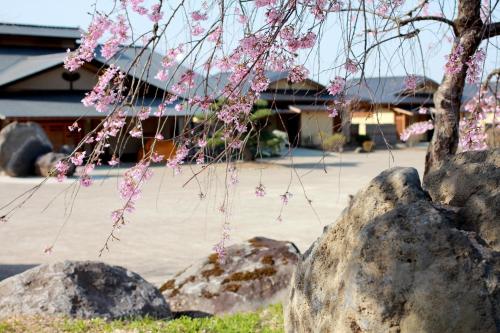 a tree with pink flowers next to some rocks at Bessou Kakei in Morioka