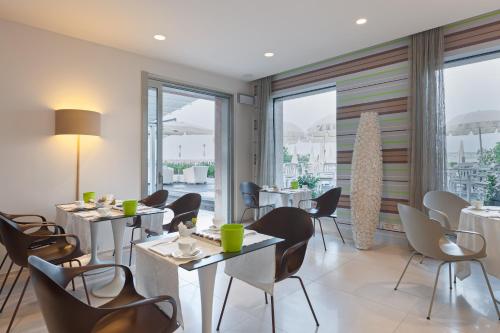 a restaurant with tables and chairs and large windows at Hotel Eden in Sirmione