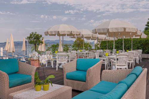 a deck with chairs and tables and umbrellas at Hotel Eden in Sirmione